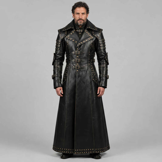 Full length studio portrait of bearded man wearing handmade black leather gothic studded duster coat with high collar and buckle straps on grey background