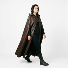 hree quarter walking shot of woman wearing handmade brown cowhide leather hooded cloak with dual chest buckle straps