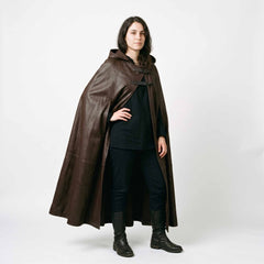 Front three quarter pose of woman modeling dark brown leather medieval cloak with hood resting on shoulders and side arm opening