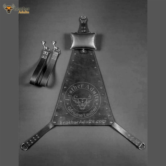 A black leather sex swing with metal rings and rivets, displayed on a dark background.