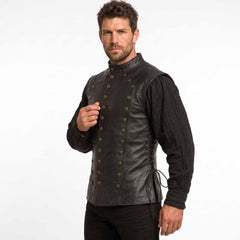 Angled perspective of a male model presenting the antique brass button detailing and side lace up grommets on a black LARP leather doublet.