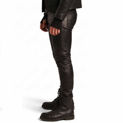 Side profile shot of fitted black leather jeans showing straight leg taper, clean outer seams, and combat boot fit