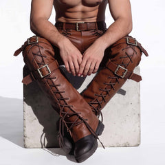 Seated perspective of man wearing brown leather steampunk pants highlighting crossed knee buckle straps and eyelet cord lacing
