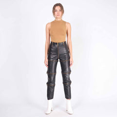 Full length front studio portrait of woman modeling high waisted black leather convertible trousers with white ankle boots