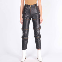 Direct front view of female model in black leather zip off trousers showing center zipper and gold horizontal leg zippers
