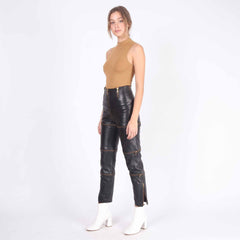 Full body standing pose of female model wearing fitted black leather zip off pants and sleeveless tan top