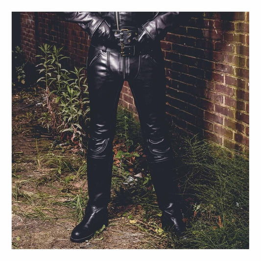 Front outdoor view of a man wearing black cowhide leather slim-fit breeches with double zippers tucked into tall biker boots.