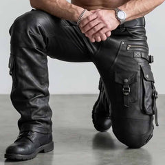 Close up view of man kneeling wearing black leather cargo pants showcasing articulated knee stitching zippered pockets and rugged leather grain