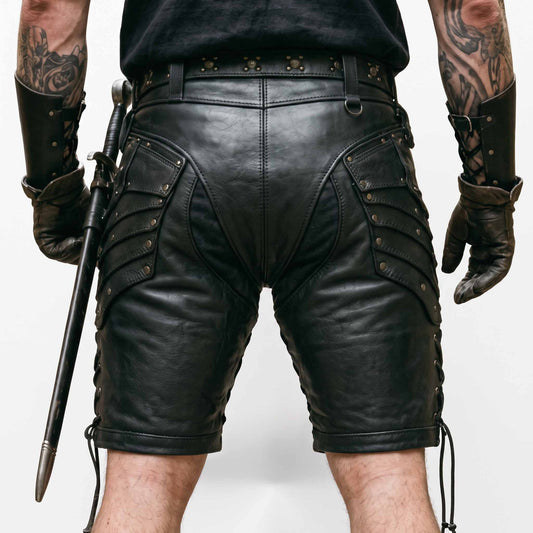 Back close up view of mens black leather warrior shorts displaying reinforced saddle seat seams, tiered hip plates, and side cord lacing