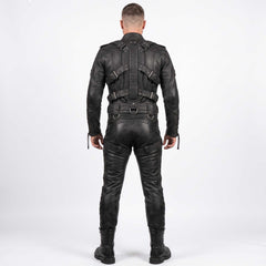 Back view of man modeling black leather bondage suit showing articulated spine harness, metal D rings, rear cross straps, and lace up legs