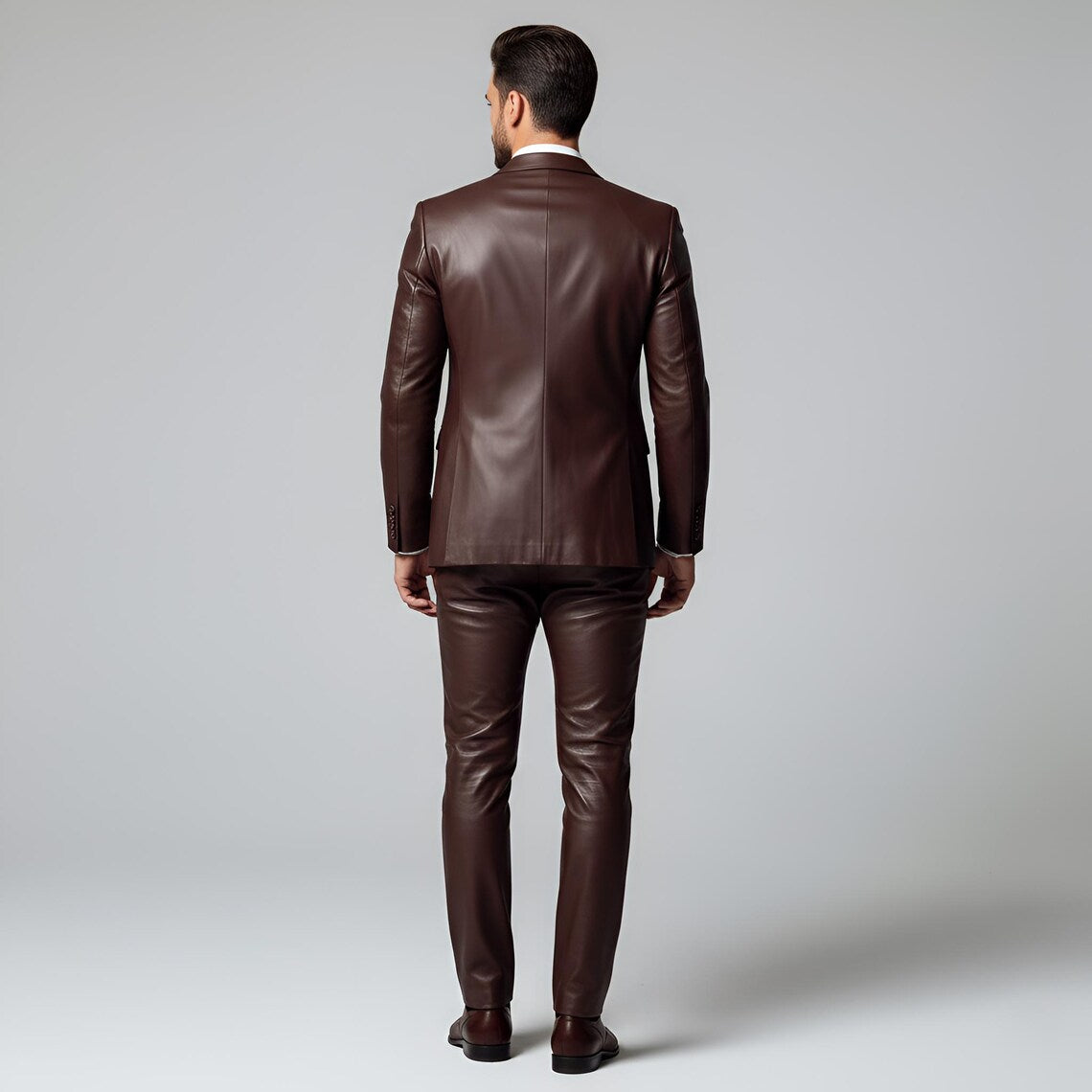 Rear view of tailored men's rich brown leather suit showing smooth back panel jacket and slim-fit matching leather trousers