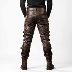 Rear full length view of mens brown leather trousers displaying 5-pocket jean styling, reinforced back seams, and wrap-around leg buckle straps