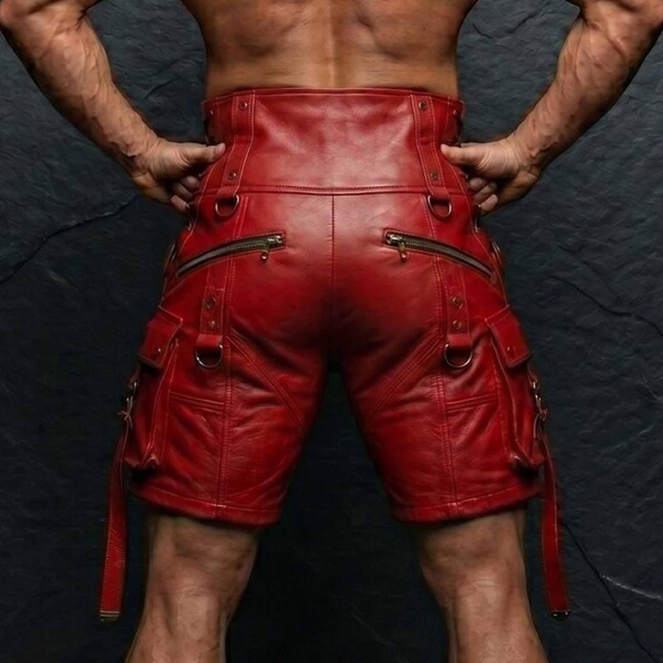 Back view of muscular man wearing red genuine cowhide leather shorts showing rear zip pockets high rise waist and hanging leg straps