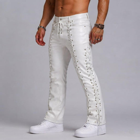 Three-quarter standing pose of man wearing white leather gothic trousers with front thigh and side eyelet lacing paired with white sneakers.