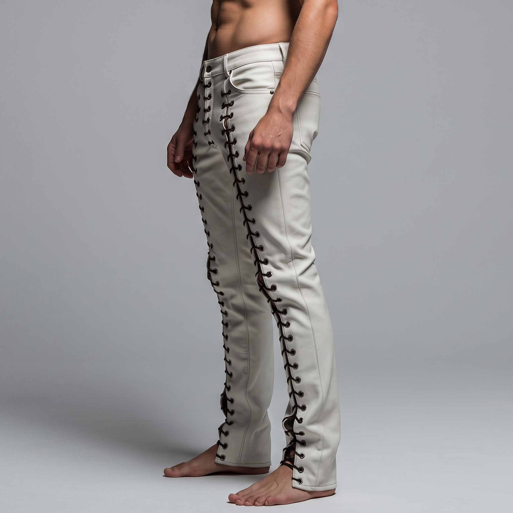 Side profile shot of tailored white leather gothic festival pants displaying full length outer leg grommet lacing and slim leg cut