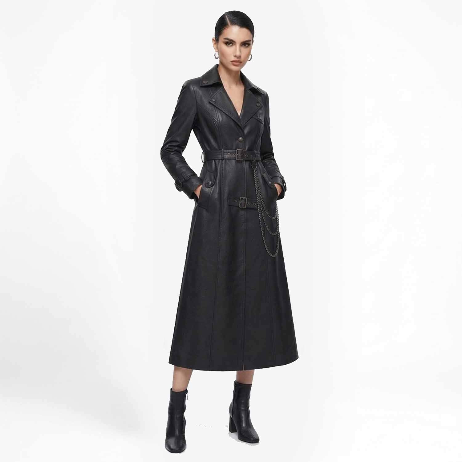 Front view of a woman wearing a long black leather trench coat with a belted waist and hanging chain detail, paired with heeled boots.