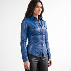Three quarter side perspective showing a brunette model wearing a handcrafted blue genuine leather button down shirt with black trousers.